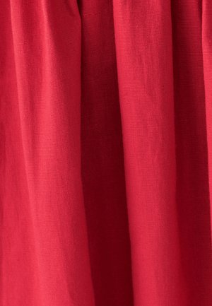 Red fabric with a smooth texture, featuring subtle folds and drapes. The material is lightweight and slightly patterned.