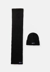 Conjunto de cachecol e gorro pretos com textura canelada, apresentando um design de malha texturizada, material macio e pequenas etiquetas de marca no cachecol e no gorro.
