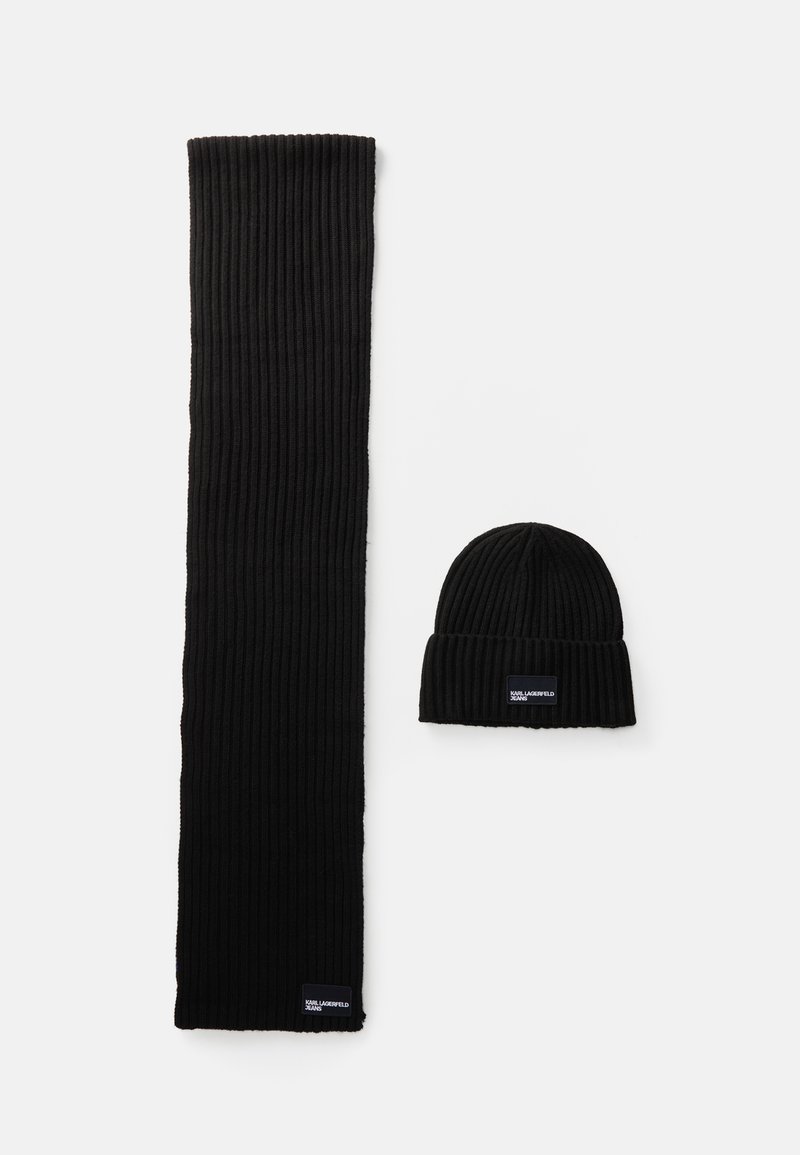 Conjunto de cachecol e gorro pretos com textura canelada, apresentando um design de malha texturizada, material macio e pequenas etiquetas de marca no cachecol e no gorro.