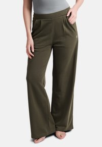 Olijfgroene wijde broek gemaakt van zachte stof, met een comfortabele elastische tailleband en zijzakken. Geen opmerkelijke patronen of accenten.