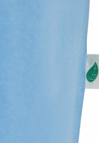 Svijetloplava tkanina glatke teksture, s malom bijelom etiketom s dizajnom zelenog lista na rubu. Jednostavan i minimalistički dizajn.