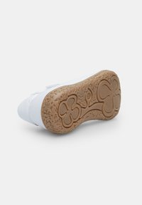 Vit sneaker med en texturerad gummisula som har ett blommigt mönster. Slätt ovandelmaterial med förstärkt sömnad på sidorna.