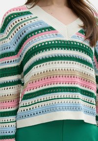 Multikleurige gebreide trui met V-hals, met strepen in groen, roze, blauw en roomkleur, met een open geweven textuur.