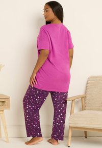 Purppuran värinen puuvillapajamasetti, jossa on lyhyet hihattomat vaaleanpunaiset paidat ja kuvioidut housut, joissa on tähtiä ja sydämiä valkoisissa ja vaaleanpunaisissa sävyissä.