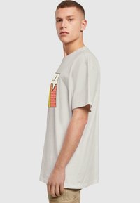 Camiseta de algodón gris con un estampado gráfico colorido y un diseño de burbuja de diálogo. Corte de ajuste relajado con mangas cortas.