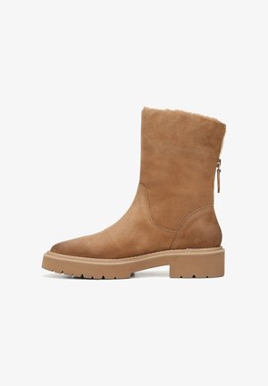 Bottines en suède marron avec une tige texturée, bout rond et semelle en caoutchouc épaisse. Dotées d'une fermeture éclair sur le côté.