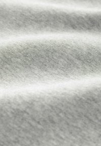 Tela gris claro con una superficie suave y texturada, que presenta sutiles variaciones en el tono y suaves pliegues que generan profundidad y dimensión.