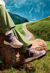 Buty węderskie mają beżową siateczkę, czarne akcenty i różowe sznurówki, nakrapianą białą podeszwę środkową oraz teksturowaną czarną podeszwę zewnętrzną.