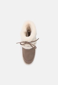 Stivale alla caviglia in suede marrone con un risvolto in shearling color crema, rifinito con un laccio e cuciture decorative lungo la suola. Texture morbida in tutto il prodotto.