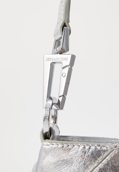 Dettaglio di una borsa a mano metallica argentea con una chiusura lucida in argento con il nome del brand inciso, e un corpo in pelle texturizzata.