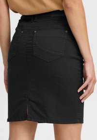 Black denim skirt with a fitted design, featuring back pockets, a front slit, and subtle stitching details.
