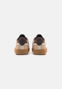 Beige and brown sneakers with a textured upper, gray accents, and a gum sole. Rounded toe and padded collar for comfort.