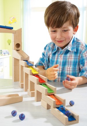 Wooden marble run with ramps in blue, red, yellow, and green. Smooth, natural wood finish with marbles rolling down the sloped tracks.