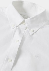 Biała koszula zapinana na guziki z kołnierzykiem typu spread, białymi guzikami i subtelnym haftowanym logotypem na piersi. Gładki materiał bawełniany.