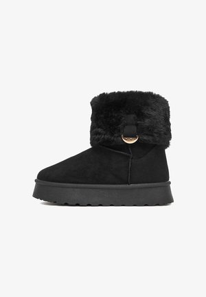 Črni semiš gležnarji z ovratnikom iz umetnega krzna, z okroglim prstom, ravnim gumijastim podplatom in kovinskim poudarkom na strani.