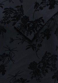 Tissu noir avec un motif floral texturé comprenant diverses feuilles et grappes de fleurs sur un fond sombre.