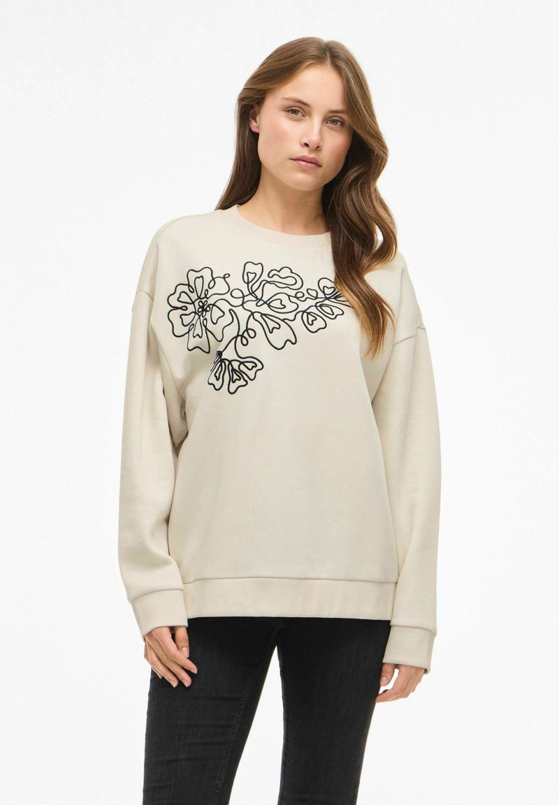 Ljusbeige sweatshirt med svart blomsterbroderi, långa ärmar och ribbade muddar. Mjuk tyg med avslappnad passform.