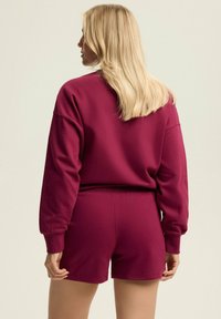 Mauve sweatshirt and matching shorts set. Sweatshirt features long sleeves and relaxed fit, while shorts have an elastic waistband and smooth texture.