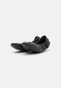 Zapatos planos de cuero negro con una textura suave y arrugada. Punta redondeada y abertura elástica. Suela de goma con un patrón para mayor agarre.