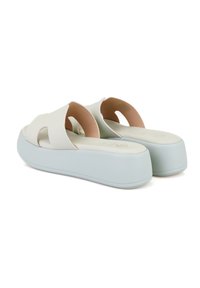 Lichtgrijze sandalen met een open teen ontwerp, voorzien van twee brede banden en een platformzool. De zool is lichtblauw met een gestructureerde afwerking.