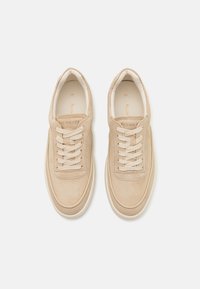 Baskets en suède beige avec une silhouette basse, un bout rond, un laçage à cinq œillets et une semelle en caoutchouc crème. Doublure intérieure douce.