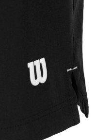 Camisa atlética negra con un logo blanco de Wilson en el dobladillo, con tejido suave, mangas cortas y una abertura lateral para mayor comodidad.