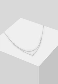 Eine silberfarbene, doppellagige Halskette mit zarten Ketten und kleinen runden Akzenten. Die Ketten haben eine glatte, glänzende Textur.