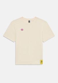 Cremfarbendes Baumwoll-T-Shirt mit kurzen Ärmeln, das ein pinkfarbenes Donut-Logo auf der Brust und ein gelbes Adidas-Etikett am Saum aufweist.