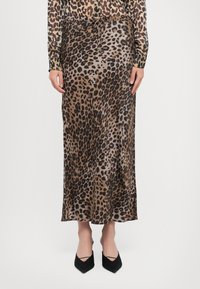 Leopardmønster, lang silkeskjørt med strikk i livet, med en glatt tekstur og en flytende design. Svarte spisse hæler fullfører antrekket.