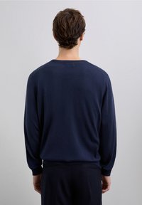 Marineblauwe trui met ronde hals en lange mouwen, gemaakt van zachte, gladde stof. Eenvoudig ontwerp met geribbelde boorden aan de mouwen en zoom.