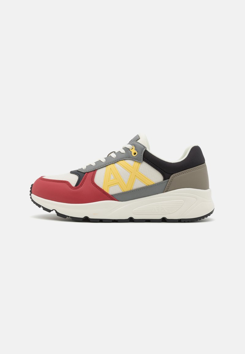 Athletic sneaker featuring a mesh upper with red, yellow, and gray accents, textured panels, laces, and a white rubber sole.