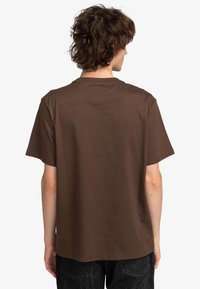 Brown cotton t-shirt with a classic crew neck, short sleeves, and a relaxed fit, shown from the back with minimal detailing.