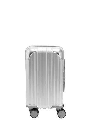 Srebrna walizka twarda z pionowymi rowkami, wzmocnionymi narożnikami i czterema obrotowymi kołami, stojąca pionowo na białym tle.