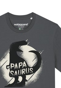 Graues Baumwoll-T-Shirt mit einer schwarzen Dinosaurier-Silhouette und dem Text "PAPA SAURUS" in fetten weißen Buchstaben, auf einem gesprenkelten Hintergrund.