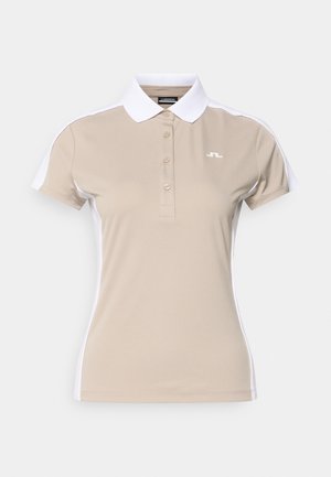 Smėlio spalvos polo marškinėliai su baltu apykakle ir šoninėmis plokštėmis, turi tris mygtukus ir mažą logotipą kairėje krūtinės pusėje. Lygaus audinio tekstūra.