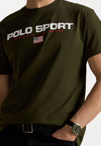 T-shirt en coton vert olive avec un texte audacieux en blanc et rouge "POLO SPORT RALPH LAUREN" accompagné d'un accent de drapeau américain. Manches courtes.