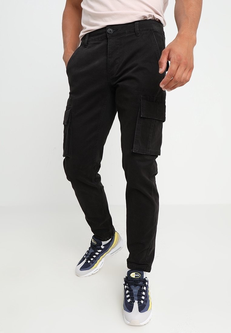 Czarna cargo ze slim fit, wykonana z bawełny, z wieloma bocznymi kieszeniami i klasycznym zapięciem na guzik. W zestawieniu z sportowymi trampkami.