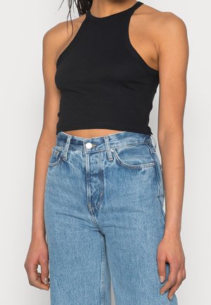 Černý žebrovaný halter crop top v kombinaci s vysoko pasem světlých modrých džínů, s klasickým zapínáním na knoflíky a zip.