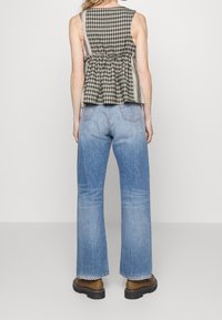 Blusa peplum a cuadros en blanco y negro con escote redondo, combinada con jeans acampanados de color azul claro y zapatos de plataforma marrones.