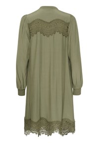 Olivza zaļa kleita ar garām piedurknēm, kurai ir mežģīņu pārklājums ap kaklu un tamborēta apdare ap apakšmalu un piedurkņu galiem.