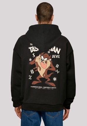 Black hoodie featuring a large cartoon graphic of the Tasmanian Devil on the back, with bold text and playful symbols in light colors.