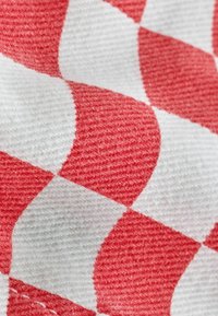 Close-up of red and white checkered fabric with visible texture and weave pattern.
