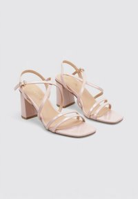 Sandalias de tacón de charol rosa pálido con múltiples correas entrecruzadas y punta cuadrada. Tacón bloque para mayor estabilidad.