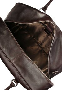 Borsa in pelle marrone con una superficie liscia, dotata di una zipper argentata e di un ampio interno foderato con un tessuto marrone scuro con marchio.