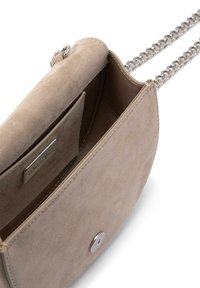 Bolso cruzado de ante beige con cadena plateada. Tiene una forma redondeada, cierre de botón en la parte frontal y un pequeño bolsillo interior.