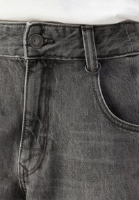 Pantalonii din denim gri au fermoar la față, cusături contrastante și o singură buzunar frontal cu închidere prin buton.