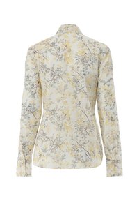 Blusa floreale con maniche lunghe, sfondo crema, motivo di fiori gialli e grigi, polsini con bottoni, colletto strutturato, texture del tessuto liscia.