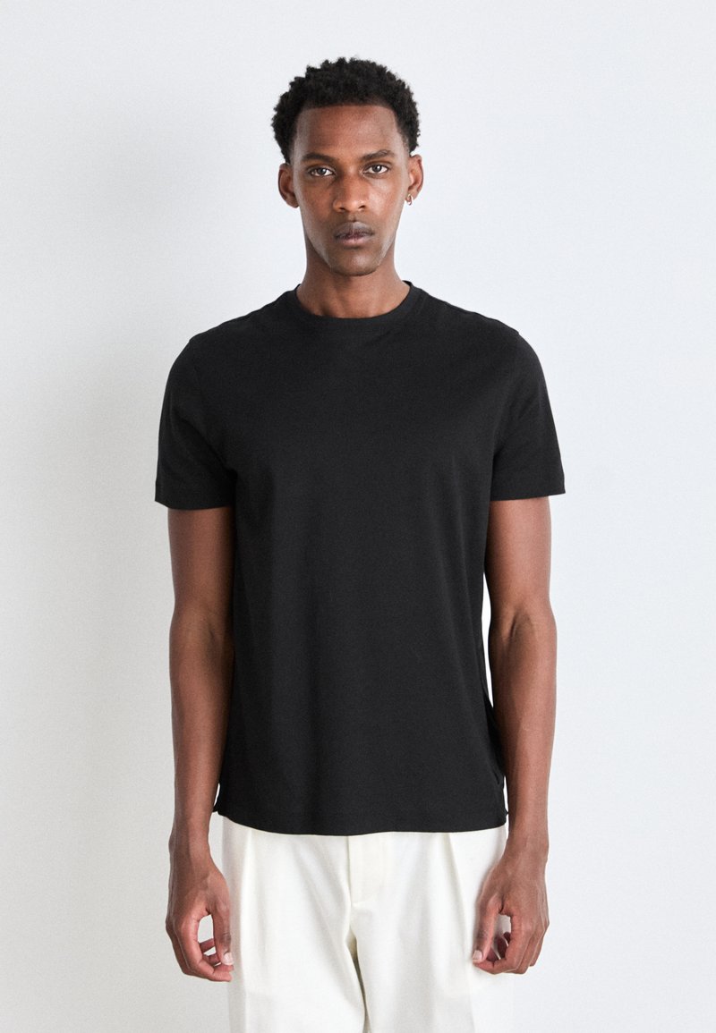 Camiseta negra de manga corta hecha de tela de algodón suave, diseño de cuello redondo, corte ajustado, sin patrones ni gráficos visibles.