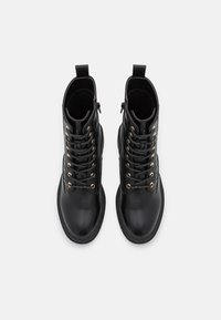 Svarta läderankelstövlar med rundad tå, guldöglor och snörning framtill. Har en sidodragkedja och texturerade detaljer.