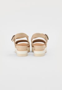 Sandales en cuir suédé beige avec deux bandes arrière, une semelle intermédiaire en jute tressé et une semelle en caoutchouc blanche. Détail de boucle en métal ajustable sur le côté.